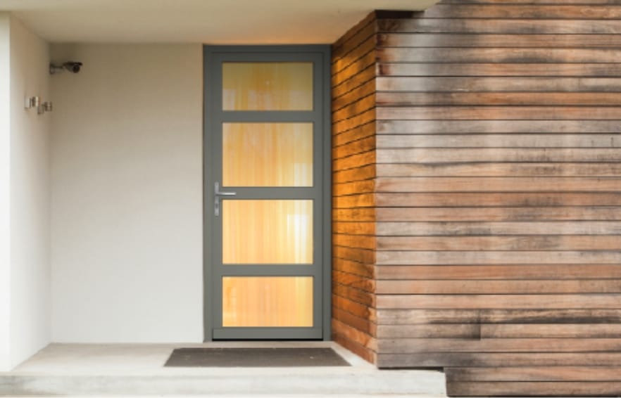 Porte d'entrée vitrée collection Vintage Bouvet couleur grise accordée au parement en bois de la façade