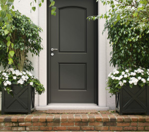Extérieur de maison avec escalier en brique, porte d'entrée grise et multiples verdures | Menuiseries Bouvet