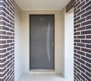 Entrée vue de l'extérieur avec porte d'entrée grise composée d'une surface vitrée et d'un décor | Menuiseries Bouvet