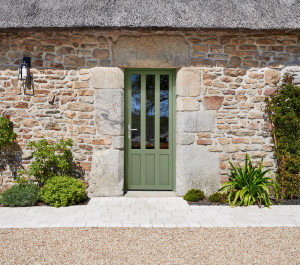 Maison traditionnelle en pierres vue extérieur avec porte d'entrée couleur verte | Menuiseries Bouvet