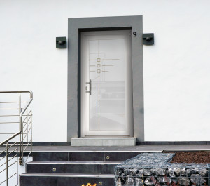 Maison vue de l'extérieur avec petites marches qui dirige vers une porte d'entrée vitrée avec décor petits carrés | Menuiseries Bouvet