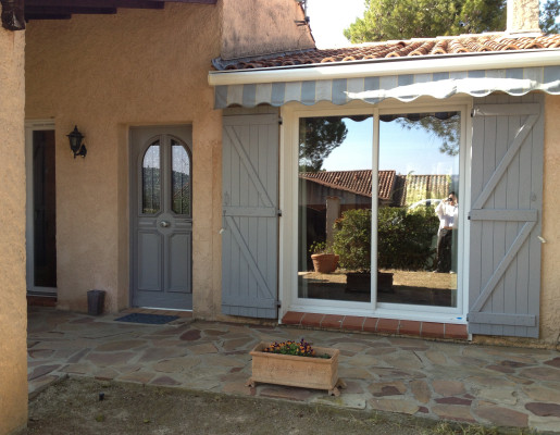 Maison traditionnelle aux murs orangés avec volets battants et portes grises
