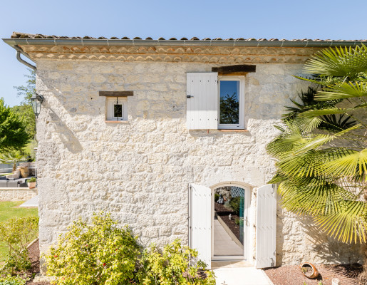 Maison vue extérieure pierres apparentes, fenêtres et volets blancs | Menuiseries Bouvet