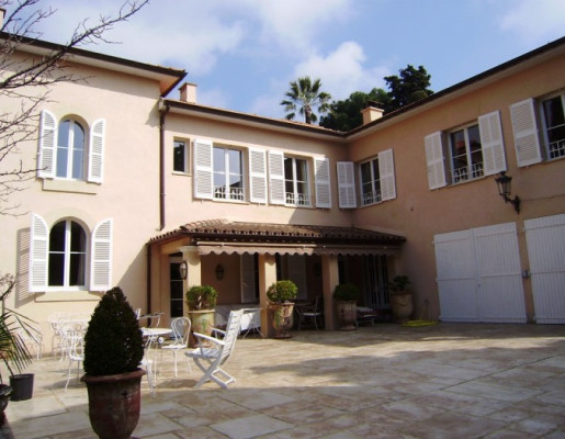 Grande maison aux multiples fenêtres blanches et terrasse avec salons de jardin | Menuiseries Bouvet