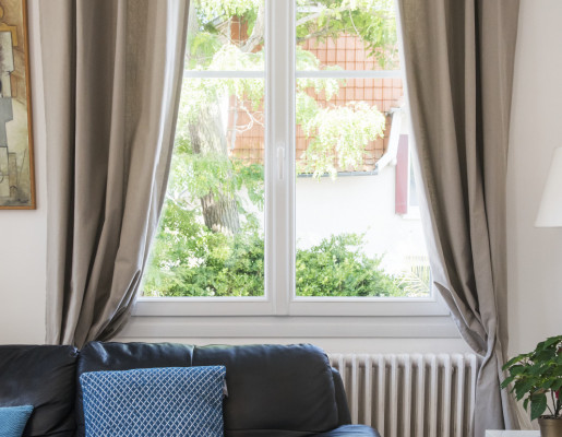 Fenêtre 2 vantaux blanche avec petits bois intégrés et rideaux taupe | Menuiseries Bouvet