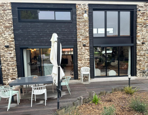 Maison avec mur en pierre et fenêtre noires | Menuiseries Bouvet