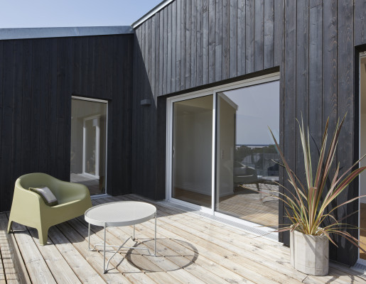 Terrasse en bois ensoleillé avec coulissant et fenêtre blanche | Menuiseries Bouvet