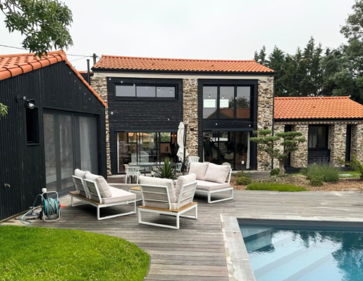 Maison en pierre vue extérieur avec toit tuiles oranges terrasse et piscine | Menuiseries Bouvet