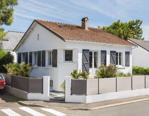 Maison de lotissement avec fenêtres blanches en PVC et volets gris | Menuiseries Bouvet